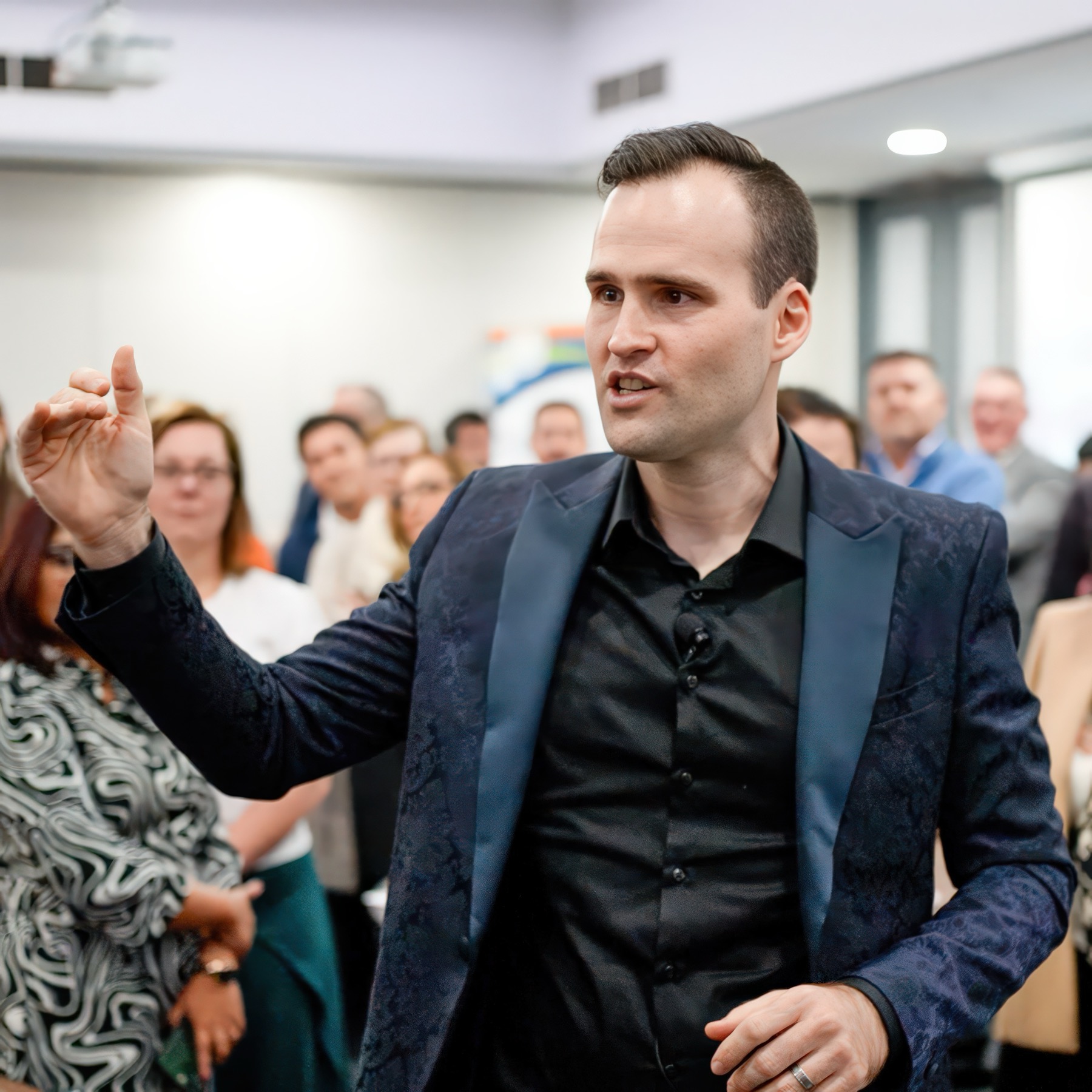 Andrew Ramsden speaking with his arm raised in front of a standing audience