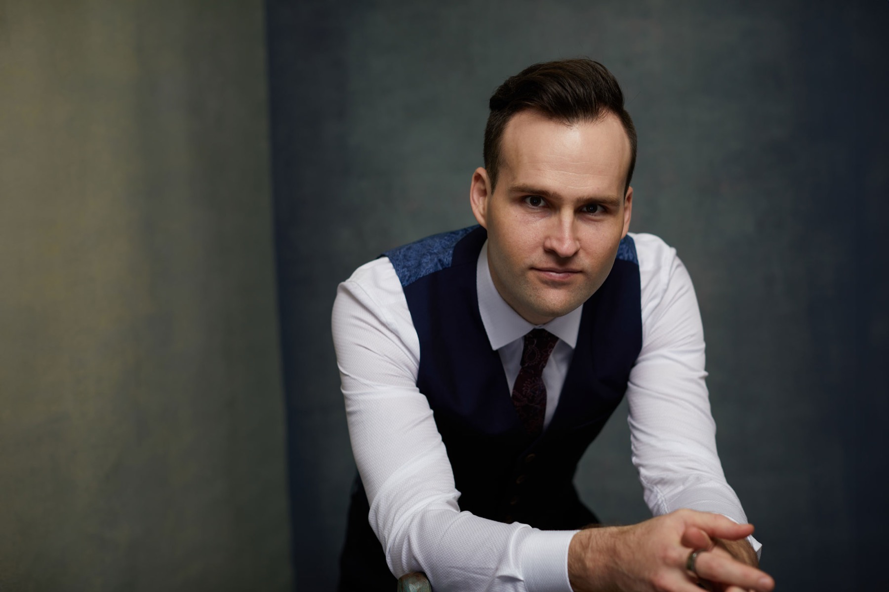 Andrew Ramsden in a dark waistcoat, leaning forward against a dark wall
